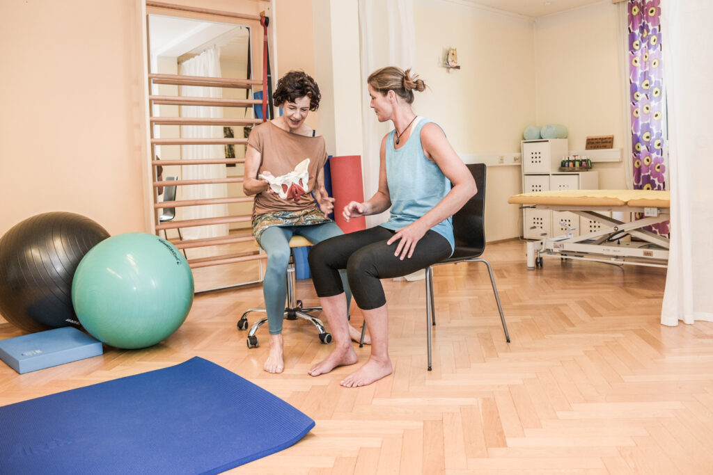 Physiotherapeutin sieht sich mit Patientin Modell von Beckenboden an