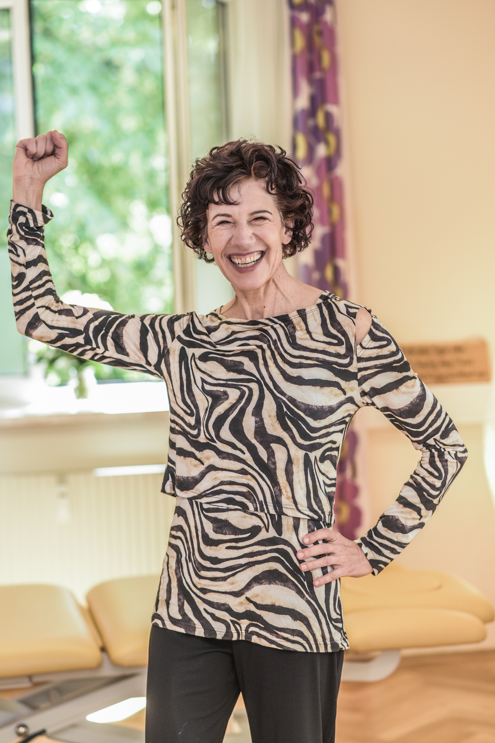 Physiotherapeutin in der Praxis streckt Faust in die Luft und hat